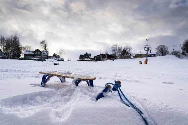 雪の降る冬の国のバック グラウンドでスキー場のリフトと青い子供そり — ストック写真