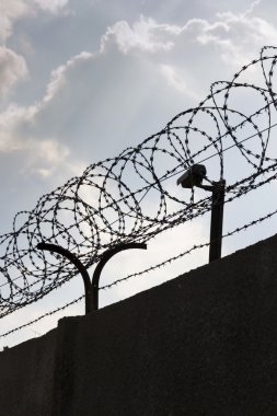 Güvenlik kamera arkasında dikenli tel çit hapishane duvarları