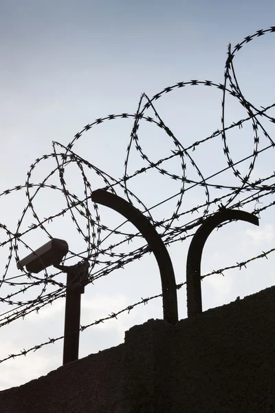 Bewakingscamera achter prikkeldraad hek rond gevangenis muren — Stockfoto