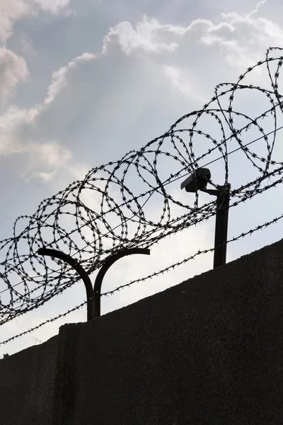 Bewakingscamera achter prikkeldraad hek rond gevangenis muren — Stockfoto