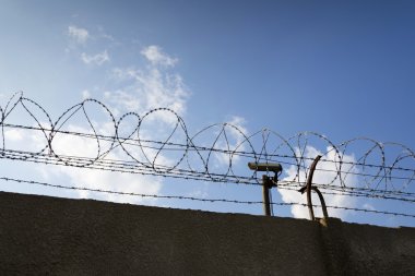 Güvenlik kamera arkasında dikenli tel çit hapishane duvarları