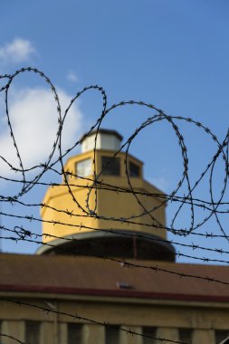 Hapishane duvarları etrafında dikenli tel çit arkasındaki Koruma Kulesi