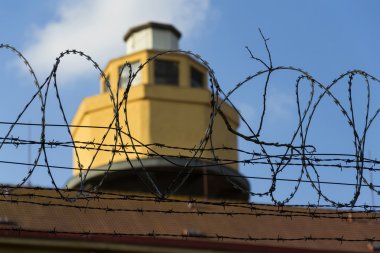 Hapishane duvarları etrafında dikenli tel çit arkasındaki Koruma Kulesi