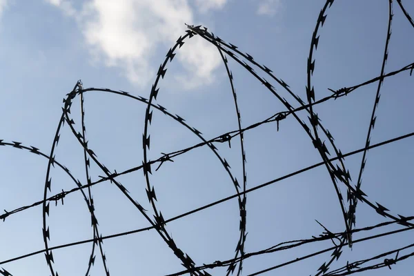 Prison wall barbed wire fence with blue sky in background — Stock Photo, Image