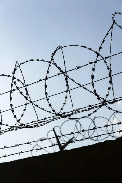 Gevangenis muur prikkeldraad hek met blauwe hemel in achtergrond — Stockfoto