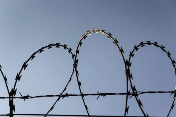 Gevangenis muur prikkeldraad hek met blauwe hemel in achtergrond — Stockfoto