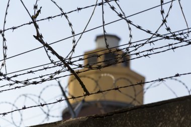 Hapishane duvarları etrafında dikenli tel çit arkasındaki Koruma Kulesi