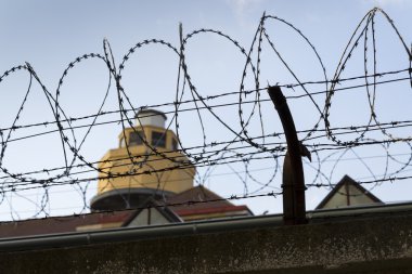 Hapishane duvarları etrafında dikenli tel çit arkasındaki Koruma Kulesi