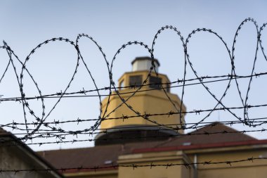 Hapishane duvarları etrafında dikenli tel çit arkasındaki Koruma Kulesi