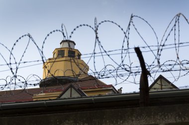 Hapishane duvarları etrafında dikenli tel çit arkasındaki Koruma Kulesi