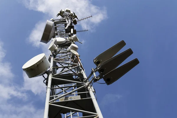 Передавачі мобільних телефонів на телекомунікаційній вежі в сонячний день — стокове фото