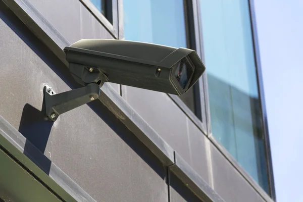 Telecamera di sicurezza grigia attaccata a pareti finestre blu sullo sfondo — Foto Stock