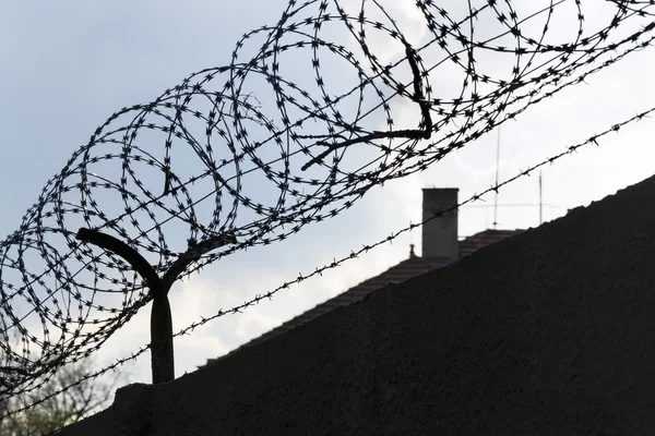 Prikkeldraad hek rond gevangenis muren blauwe hemel in achtergrond — Stockfoto