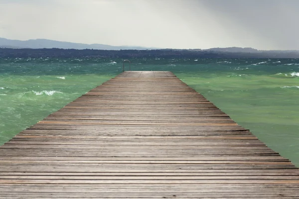 Cais de madeira com ondas no Lago di Garda, Sirmione, Itália — Fotografia de Stock