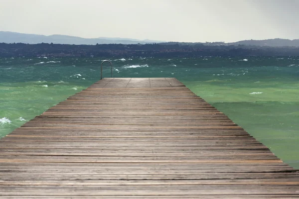 Cais de madeira com ondas no Lago di Garda, Sirmione, Itália — Fotografia de Stock