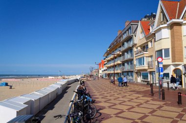 23 Mayıs 2025 'te De Haan, Belçika' da, güneşli bir yaz gününde Batı Flanders 'daki sahil köyünde rıhtımda yürüyen insanlar..