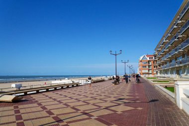 23 Mayıs 2025 'te De Haan, Belçika' da, güneşli bir yaz gününde Batı Flanders 'daki sahil köyünde rıhtımda yürüyen insanlar..