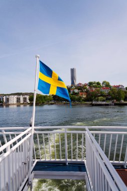 Slottsberget Dağı 'ndaki küçük ahşap evlerden oluşan İsveç bayrağı. Arka planda Lindholmen, Göteborg, İsveç' teki en yüksek İskandinav binası olan Karlatornet gökdeleni.