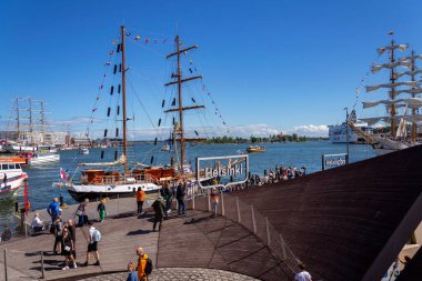 Helsinki 'li insanlar, güneşli bir yaz gününde Finlandiya' nın başkenti Helsinki 'de güzel yelkenli teknelerinin demirlediği büyük beyaz mektuplardan imza atıyorlar..