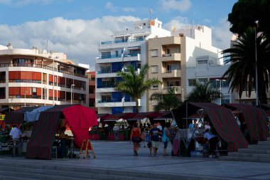 Turistler ve yerel halk 10 Temmuz 2019 'da İspanya' nın El Medano kentinde deniz kenarındaki caddelerde yürürler..