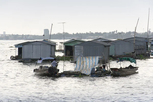 Ratty boats and raft houses with fish cages floating on Mekong river — Stock Photo, Image