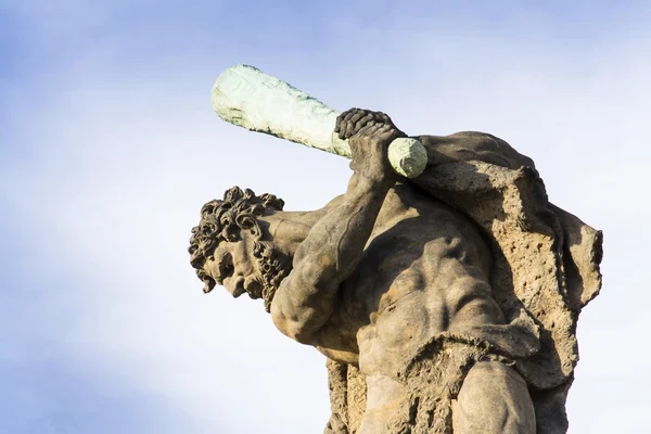 Primer plano de la estatua del luchador sosteniendo el club mirando hacia abajo con el cielo azul en el fondo — Foto de Stock