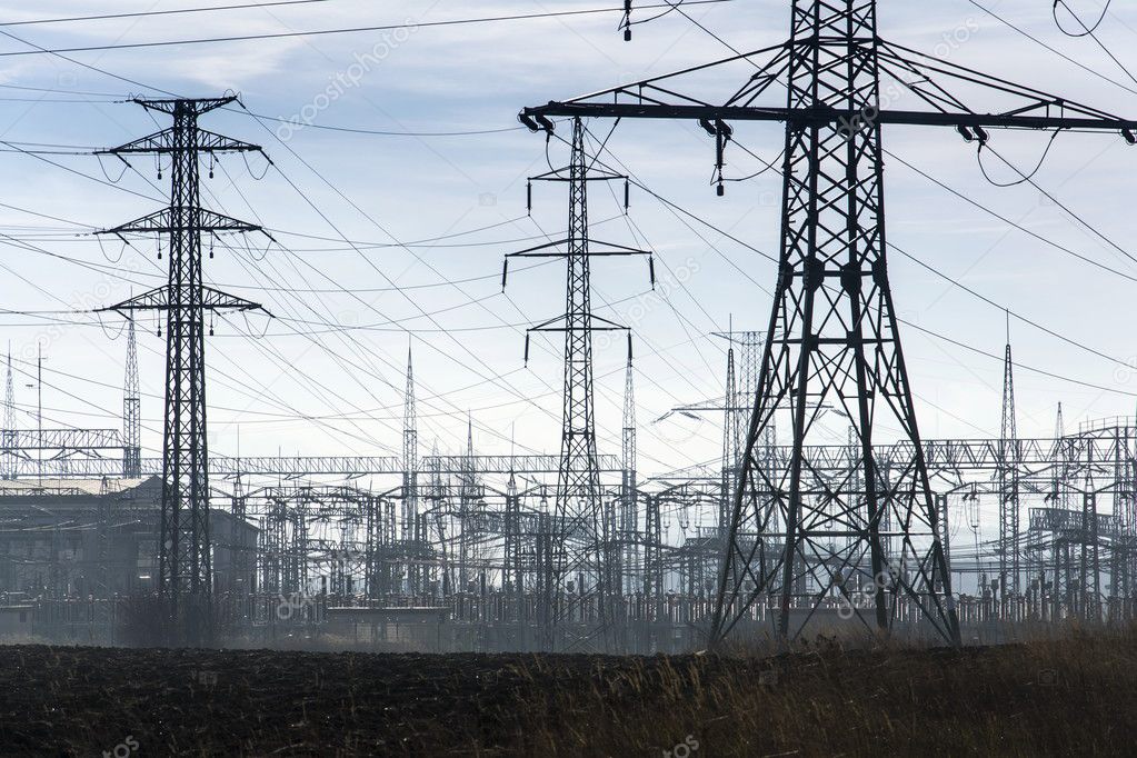 Electricity pylons with distribution power station blue cloudy sky background