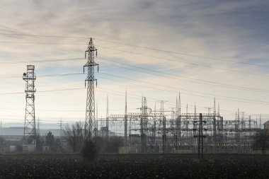 Elektrik direkleri ve dramatik bulutlu gökyüzü ile dağıtım güç istasyonu