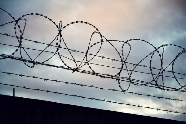 Prikkeldraad hek aangesloten rond gevangenis muren — Stockfoto