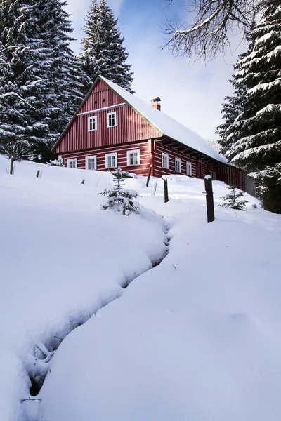 Rött trä stuga i ett frostigt snöiga land i solig vinterdag — Stockfoto