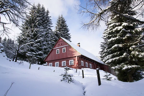 Cabaña roja de madera en un país helado y nevado en un soleado día de invierno — Foto de Stock