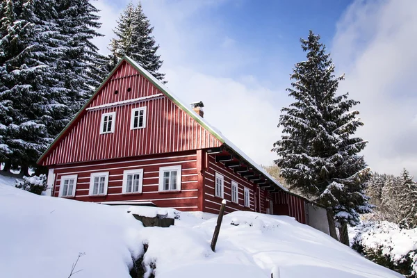 Cabaña roja de madera en un país helado y nevado en un soleado día de invierno — Foto de Stock