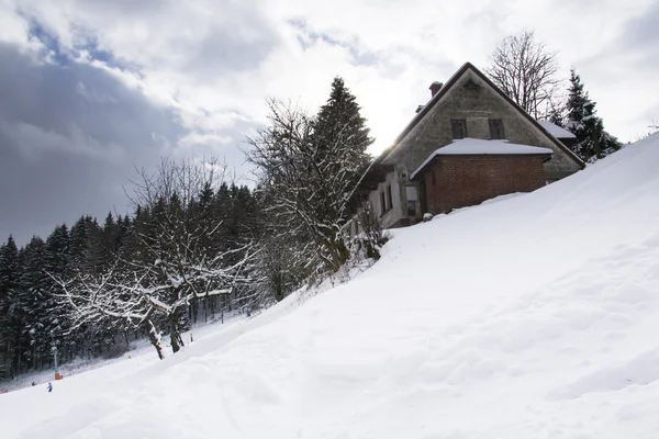 Casa cubierta de nieve en un país de montañas heladas — Foto de Stock