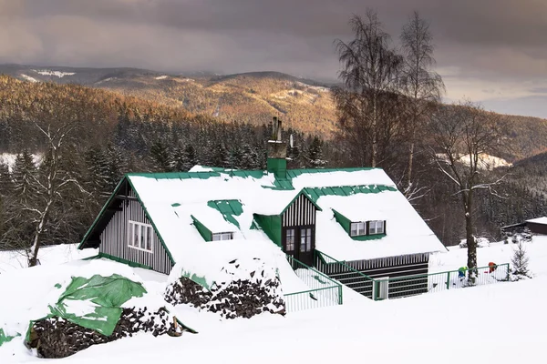 Casa cubierta de nieve durante el atardecer en un país de montañas heladas — Foto de Stock