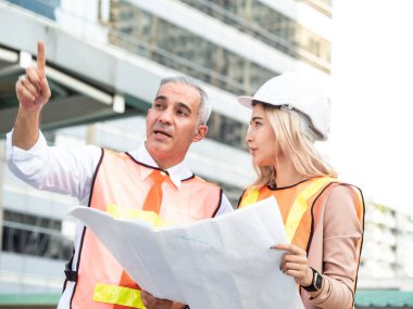 Ustabaşı mühendis ve işkadını müdürü neşeli bir şekilde parmakla işaret ederek proje endüstrisi mimarisi inşaat teknolojisi dijital depo inşaatı hakkında konuştu.