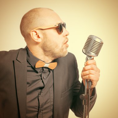 Tıraşsız kel adam mikrofon ile