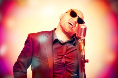 Tıraşsız kel adam mikrofon ile