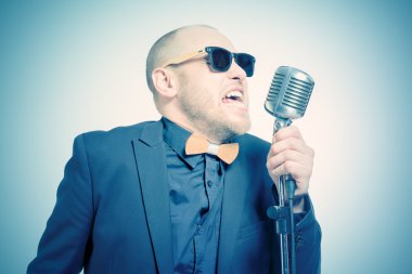 Tıraşsız kel adam mikrofon ile