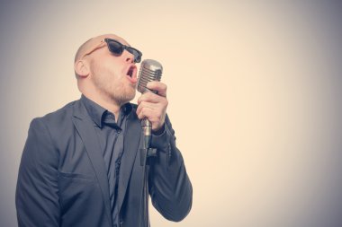 Tıraşsız kel adam mikrofon ile