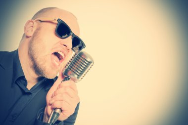 Tıraşsız kel adam mikrofon ile