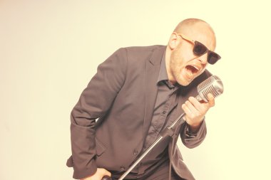 Tıraşsız kel adam mikrofon ile