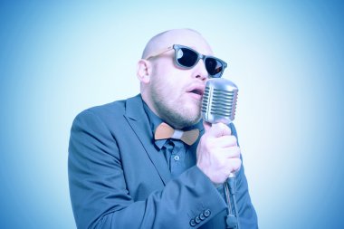 Tıraşsız kel adam mikrofon ile