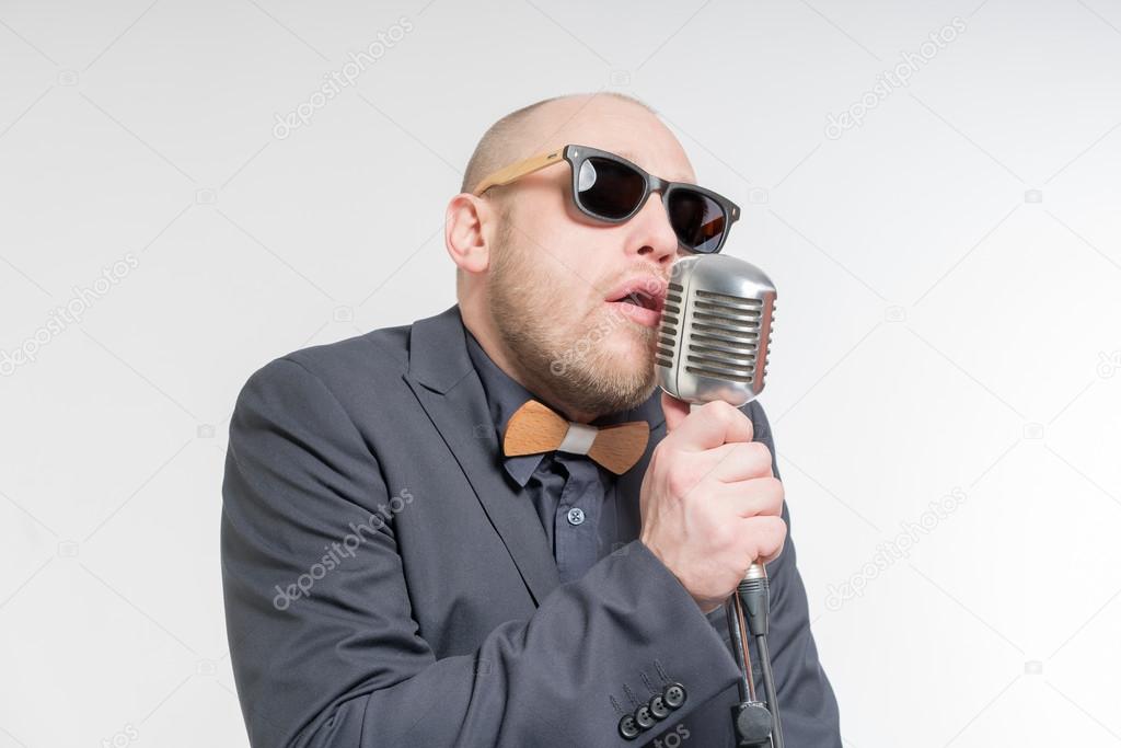 Unshaven bald man with microphone