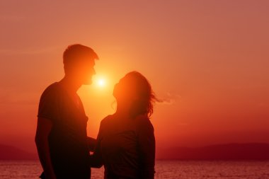 Genç çift sahilde günbatımı ayakta zevk.