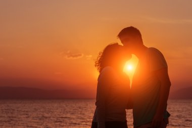 Genç çift sahilde günbatımı ayakta zevk.