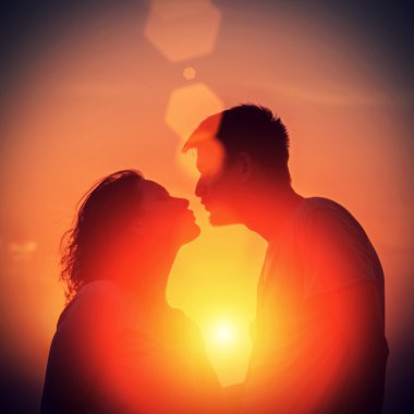 Genç çift sahilde günbatımı ayakta zevk.