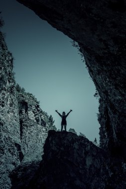 Gökyüzü mağara yakınındaki bir kayanın üzerinde duran bir kadın silüeti