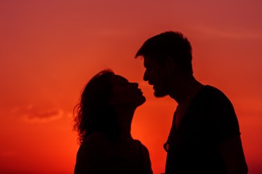 Genç çift sahilde günbatımı ayakta zevk.