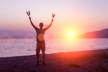 Şiş ve eller yukarı Barbekü ile sahilde duran genç adam