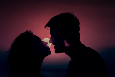 Genç çift sahilde günbatımı ayakta zevk.